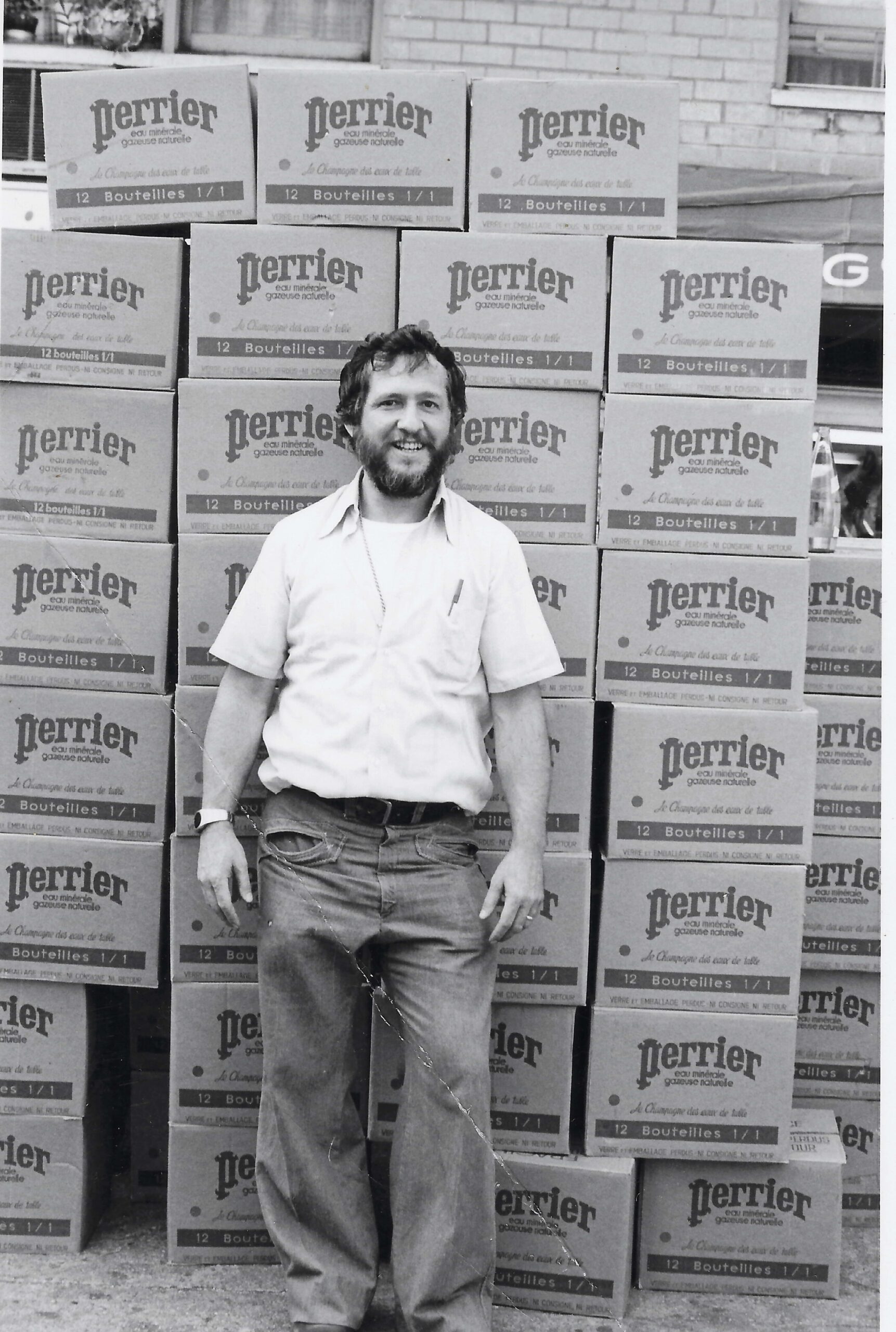 A man standing in front of boxes of beer.